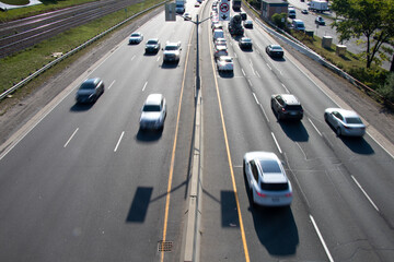 Blurred traffic passes below on a busy multi-lane highway on a sunny morning.
