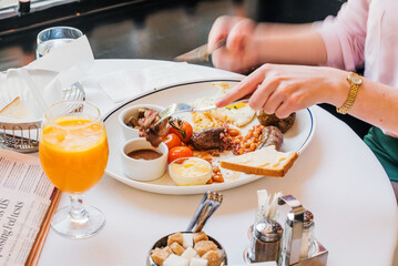 female hands holding fork and knife while having tasty breakfast at modern european cafe