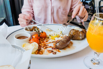 female hands holding fork and knife while having tasty breakfast at modern european cafe