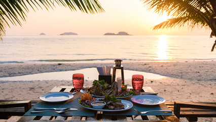 Dinner table during sunset on a beach with fish and Thai food.Romantic dinner table © Fokke Baarssen