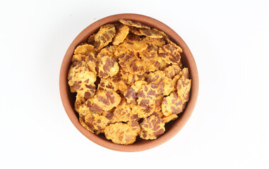 A popular Indian street snack called Chana jor garam made from flattened chickpeas that are roasted and spiced placed in a terracotta bowl placed on a white background 