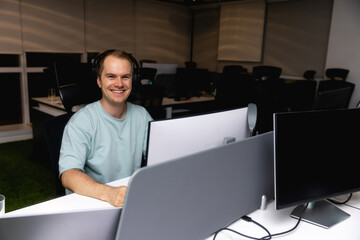 Happy young businessman using computer at his office desk.