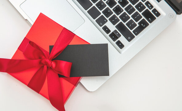 Red gift box and computer laptop on white background, top view,