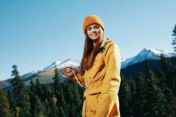 Woman smile with teeth happiness and laughter tourist in yellow raincoat with red hair travel in the fall and hiking in the mountains in the sunset sunshine freedom