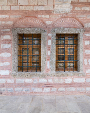Two adjacent wooden arched windows in an old red and white stone bricks wall, near Eyup Sultan Mosqoe, Istanbul, Turkey