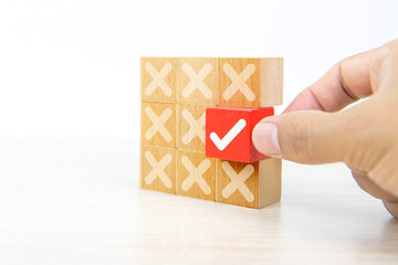 Hand choose check mark on cube wooden toy block with cross symbol for true or false changing...