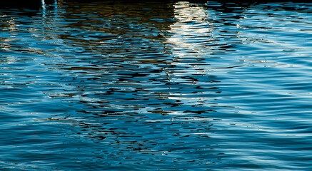 Reflection in a lake creates abstract patterns with light, shadows, and color. 