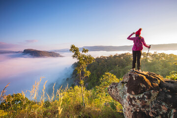 Young woman in red jacket hiking on Pha Muak mountain, border of Thailand and Laos, Loei province, Thailand.