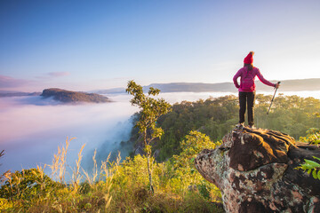 Fototapeta premium Young woman in red jacket hiking on Pha Muak mountain, border of Thailand and Laos, Loei province, Thailand.