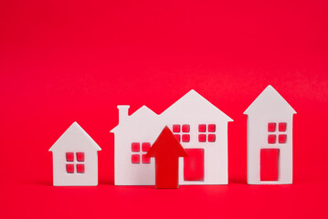 Coins on a table, a red up arrow and house. The concept of the rising price of real estate