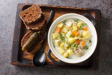 Ogorkowa Polish Sour Pickle Soup closeup on the pot on the wooden tray. Horizontal top view from...