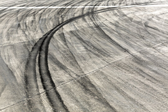 Background with tire marks on road track, Car track asphalt pavement background at the circuit, Abstract asphalt road background with crossing of tires tracks, Black tyre mark on asphalt road.