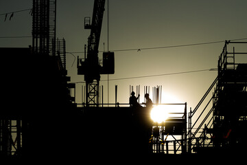 Builder workers working on construction site and sunset, beam, steel structure. Workers build large buildings on the construction site. Workers silhouette on construction safety working.blur