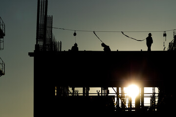 Builder workers working on construction site and sunset, beam, steel structure. Workers build large...