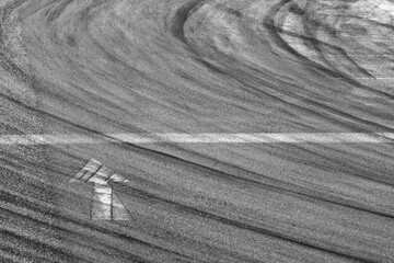 Background with tire marks on road track, Car track asphalt pavement background at the circuit, Abstract asphalt road background with crossing of tires tracks, Black tyre mark on asphalt road.