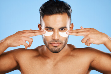 Man, eye patches and beauty for skincare, cosmetics or facial products against a blue studio...