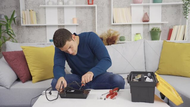 The man is repairing household appliances at home.
Inexperienced young man working repairing home appliance.

