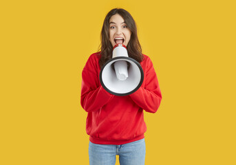 Young brunette woman wearing red sweatshirt is laughing talking in loudspeaker on yellow...