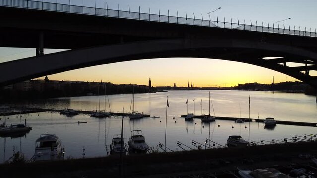 Aerial shot uner the vasterbron bridge over boats in Stockholm city at sunset time