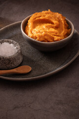 Homemade pumpkin purée for cooking in dark moody background
