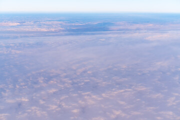 Fototapeta na wymiar Background of a pink heavenly sky with fluffy dense clouds, top view from an airplane. Can be used as advertising background, overlay. Travel concept.
