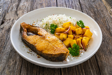 Fish dish - fried halibut with white boiled rice and avocado on wooden table
