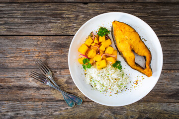 Fish dish - fried halibut with white boiled rice and avocado on wooden table
