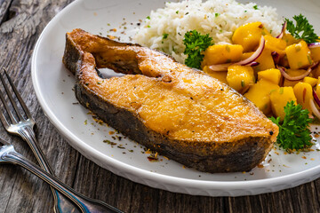 Fish dish - fried halibut with white boiled rice and avocado on wooden table
