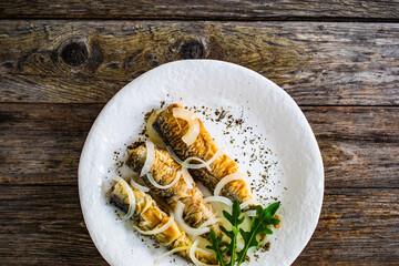 Fish dish - marinated fried herrings on wooden table
