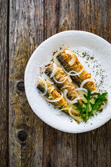 Fish dish - marinated fried herrings on wooden table
