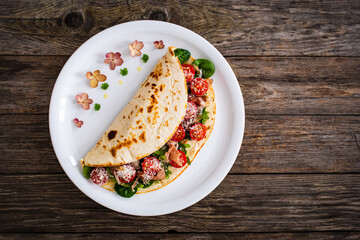 Italian piada wraps - piadina stuffed with fresh vegetable leaves, parmesan and prosciutto crudo on wooden table
