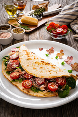 Italian piada wraps - piadina stuffed with fresh vegetable leaves, parmesan and prosciutto crudo on wooden table
