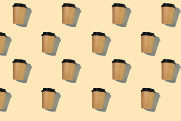 Pattern of cardboard coffee cups with a plastic lid with a hard shadow on a beige background. The...