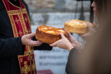 Woman and Priest hold in hands decorated Slava bread for celebration a saint in Orthodox faith....