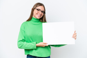 Naklejka premium Young caucasian woman isolated on white background holding an empty placard with happy expression