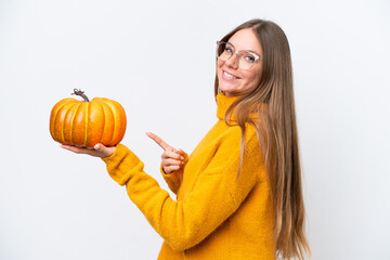 Young caucasian woman holding a pumpkin isolated on white background and pointing it