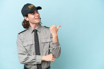 Young safeguard man isolated on blue background pointing to the side to present a product