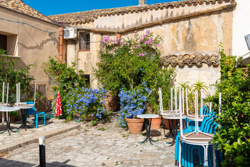 Picturesque courtyard or baglio with gastronomy in the village Scopello on Sicily. A hamlet of houses clustered around a common courtyard, on a rocky outcrop on the north coast of the island - obrazy, fototapety, plakaty