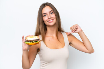 Young pretty woman holding a burger isolated on white background proud and self-satisfied