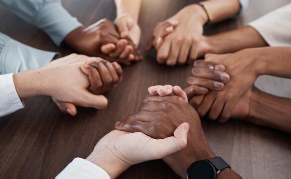 People, holding hands and care in diversity for trust, unity or community support together on a table. Hands of diverse group in collaboration for teamwork, meeting or social circle in hope at work