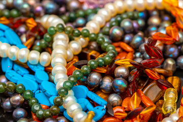 Beads and necklaces made of colored semi precious stones. Background from a variety of beautiful jewelry, multi-colored turquoise stones, amber, cat's eye, pearls.