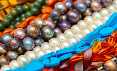 Beads and necklaces made of colored semi precious stones. Background from a variety of beautiful jewelry, multi-colored turquoise stones, amber, cat's eye, pearls.