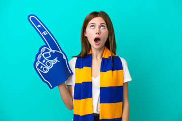 Young sports fan woman isolated on blue background looking up and with surprised expression