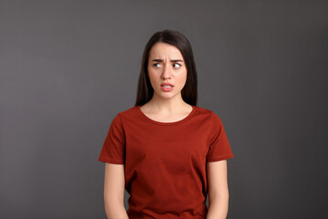 Obraz premium Portrait of emotional young woman on dark grey background. Personality concept