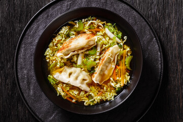 Asian Potstickers Soup in black bowl, top view
