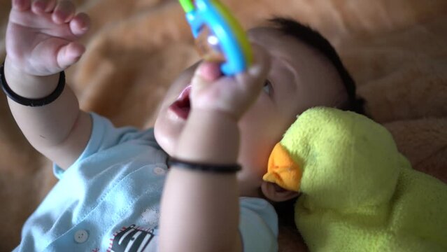 Chinese baby grab the rattle toy beside old duck plush toy