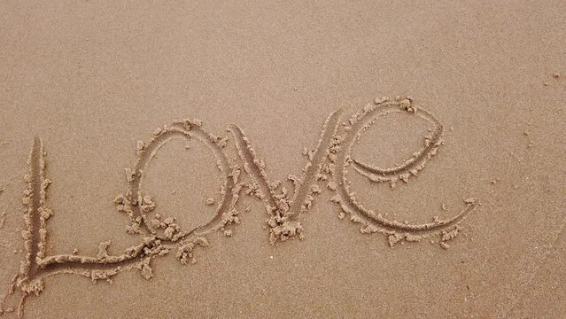 love word in sand in sea beach with ocean wave