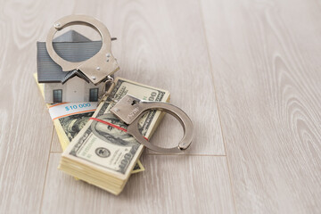 Toy house made of dollars and handcuffs on the table. Real Estate Concept
