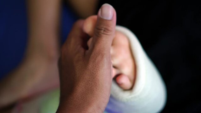 Dark hand help the toe of female broken leg with plaster bandage exercise