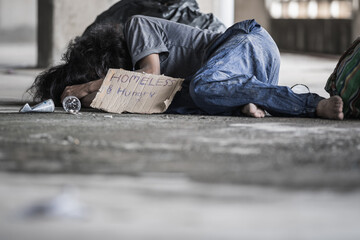 A homeless man sleeps on the street in the shadow of a building. and ask for help and money the troubles of the big modern city.